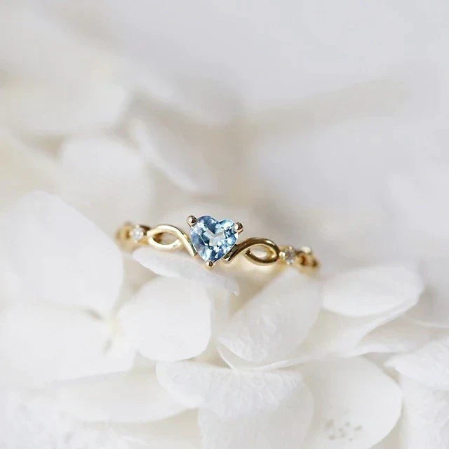 Eleganter herzförmiger Ring aus Gold mit funkelnden blauen Zirkonia-Steinen