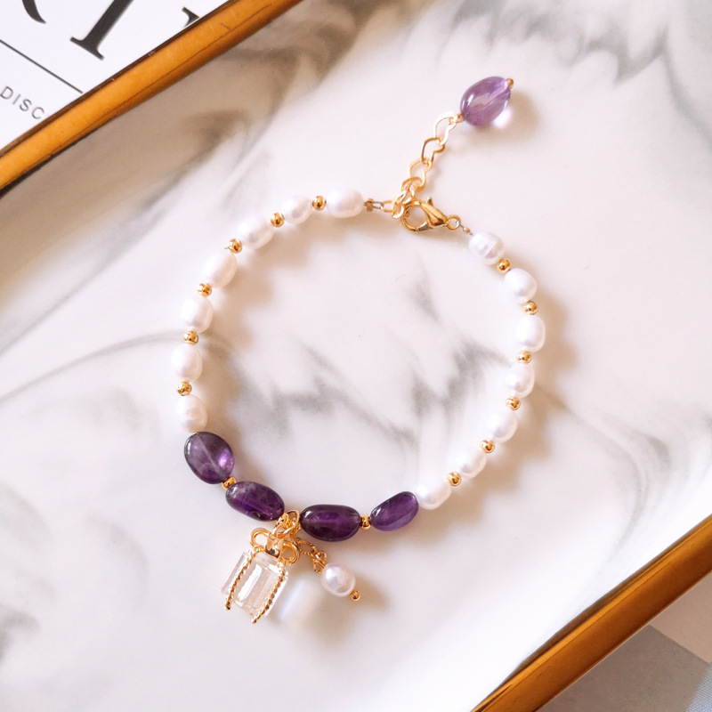 Elegantes Armband mit funkelnden lila Steinen und edlen Perlen in Gold