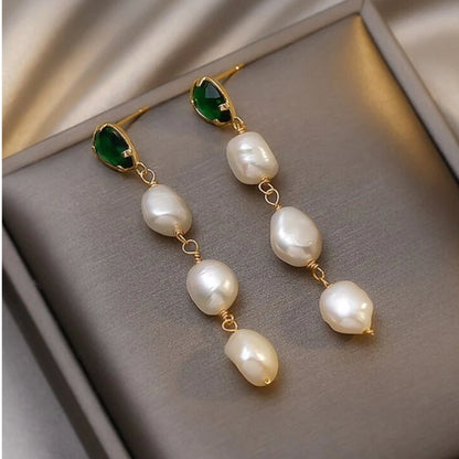 Elegante goldene Ohrringe mit funkelnden Smaragden und edlen Perlen