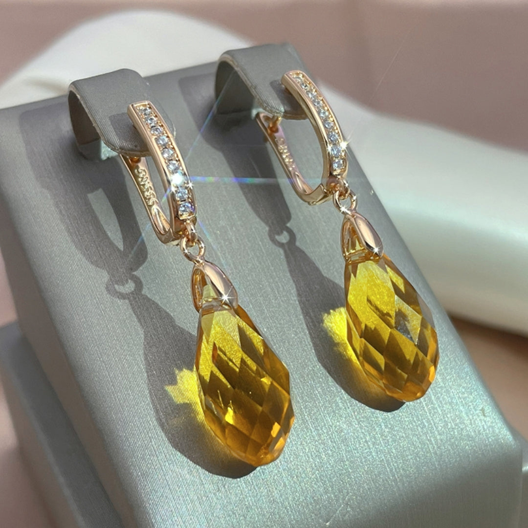 Goldene Ohrringe mit funkelnden gelben Kristalltropfen