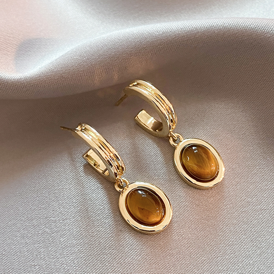 Goldene Ohrringe mit leuchtend orangefarbenen Kristallen